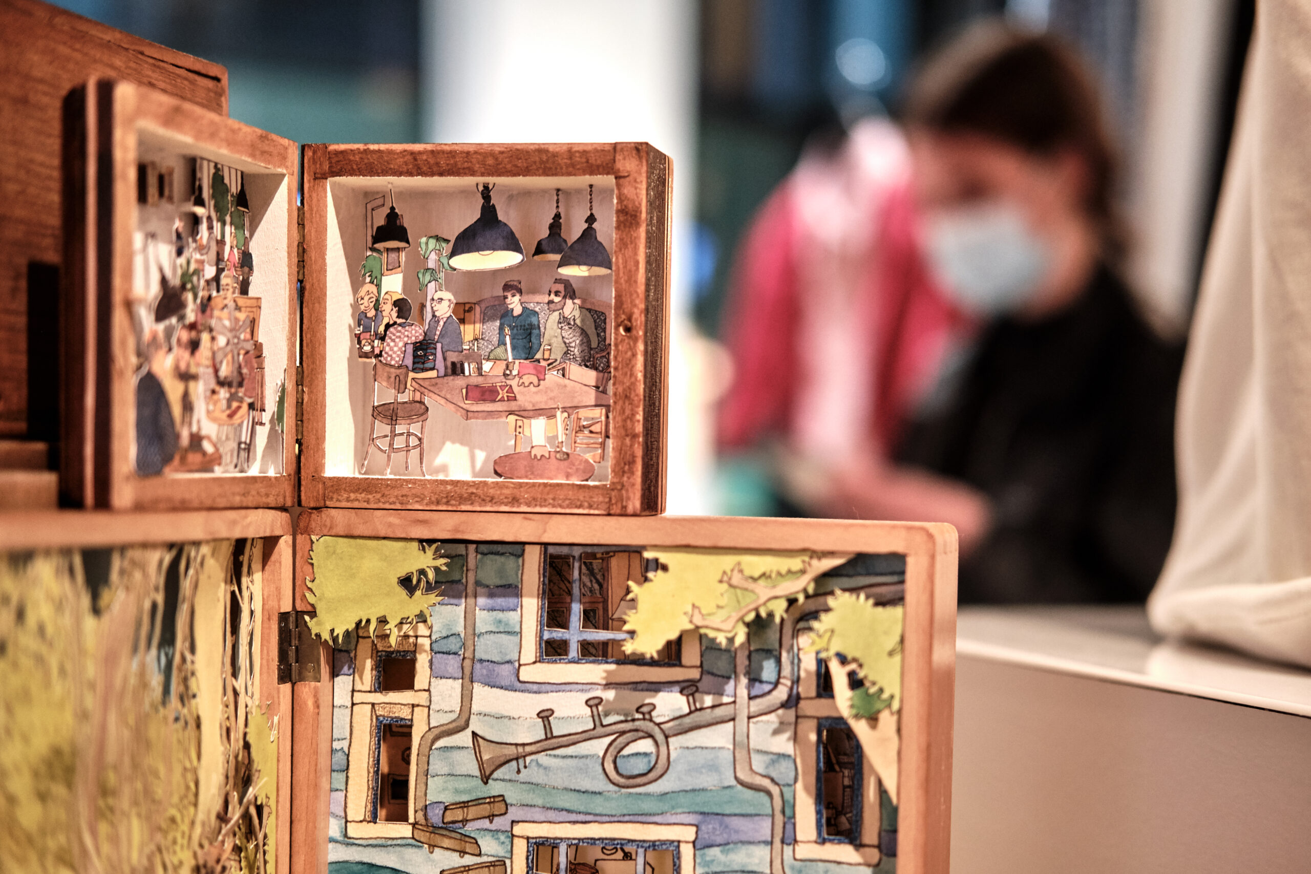 Aufklappbare Kästchen aus Holz, in denen aus Papier Szenen aus der Dresdner Neustadt gestaltet sind