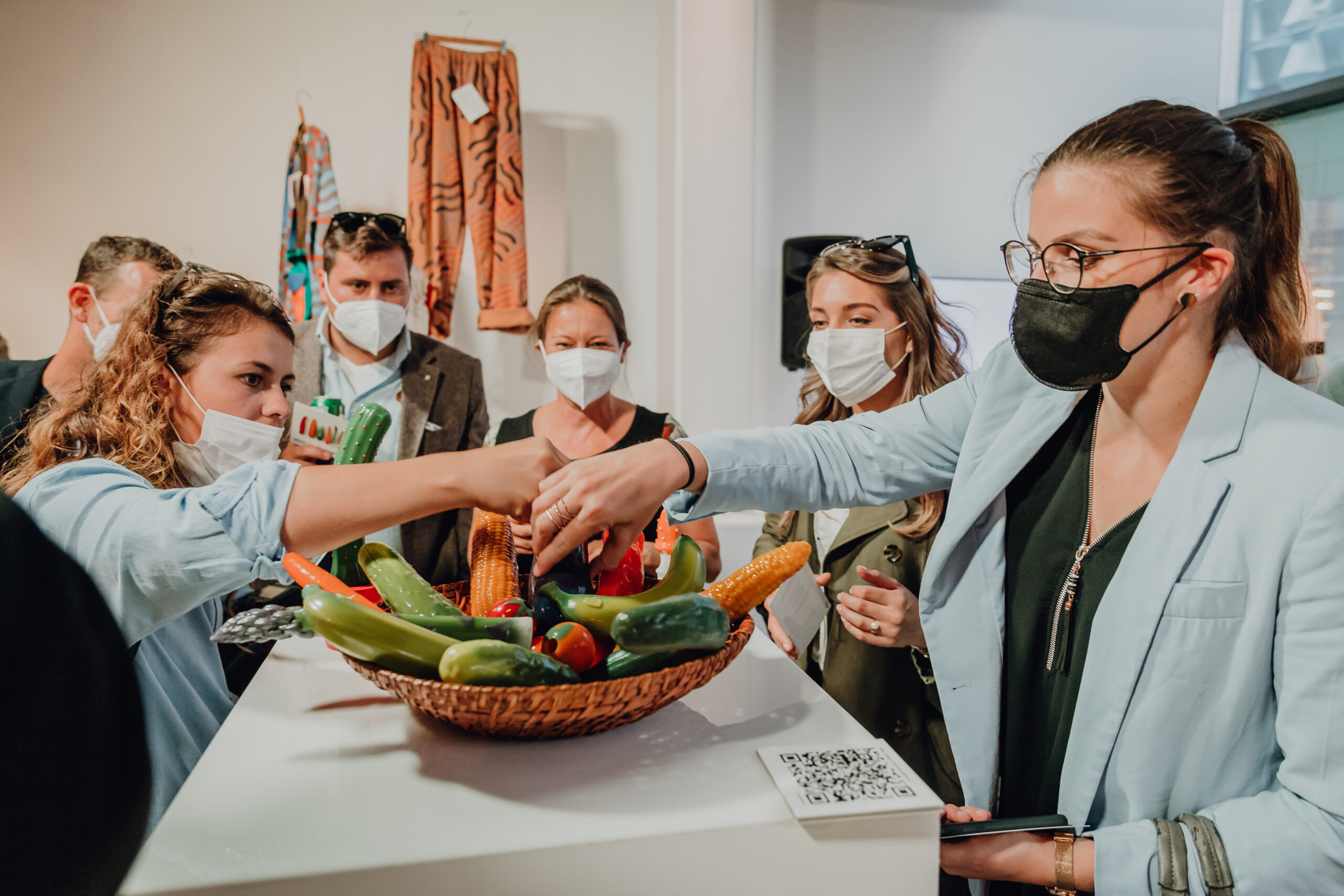 Menschen schauen einen Korb Gemüse an. Das Gemüse wie Gurke, Mais und Möhre ist aus Silikon , es sind Dildos