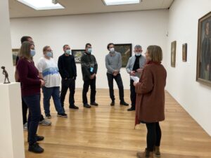 Eine Gruppe von 8 Personen steht vor Gemälden in der Städtischen Galerie