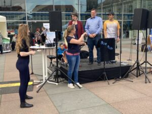 3 Personen sprechen auf der Bühne, davor steht eine Gebärdendolmetscherin.