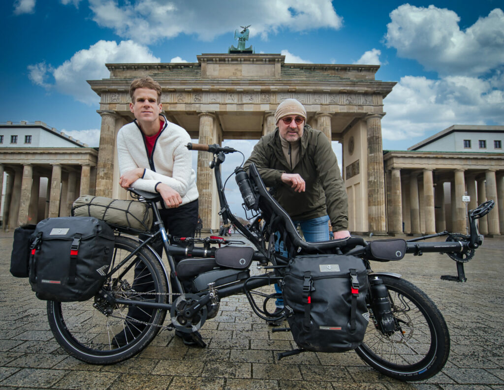 2 Personen lehnen an ihrem Tandem vor dem Brandenburger Tor in Berlin