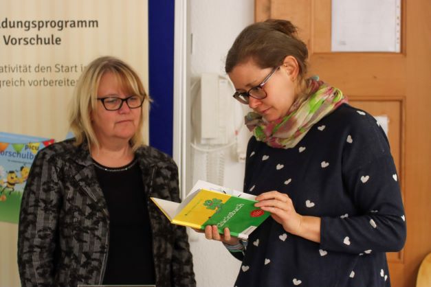 Zwei Frauen vor dem Stand des Apicula Verlages schauen sich ein Buch an