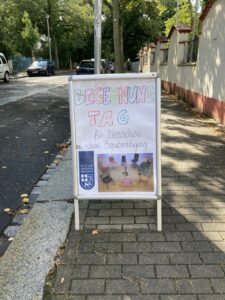 Aufsteller vor dem Eingang der Gemeinde St. Paulus, in bunten Buchstaben steht "Begegnungstag für Menschen mit und ohne Beeinträchtigungen