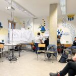 Im Seminarraum, viele Flipcharthalter, bunt gestaltet Wände, Stühle an den Wänden aufgereiht