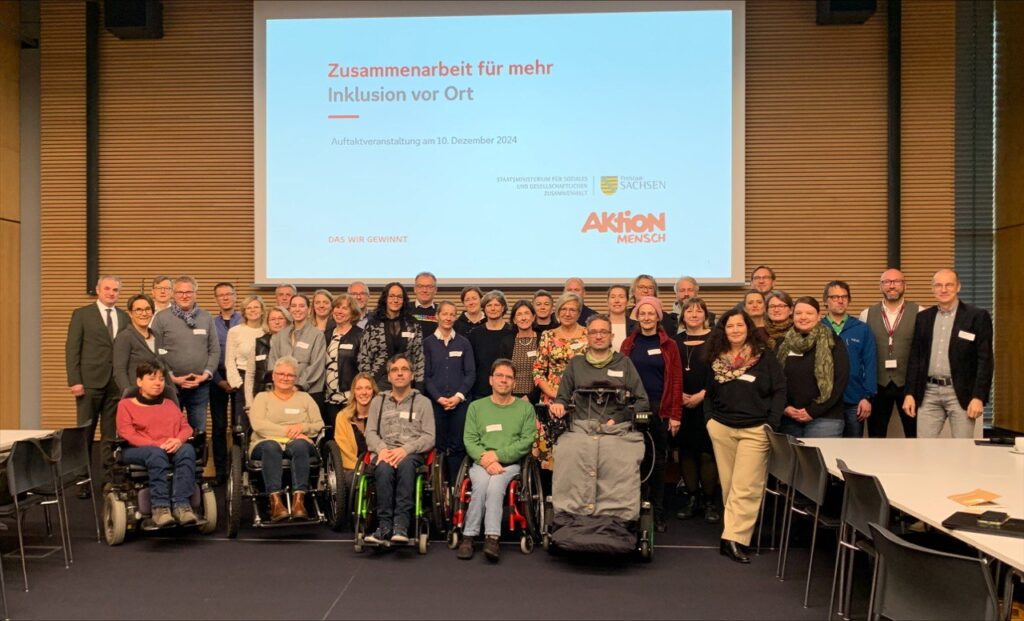 3 Reihen Personen vor einer großen Leinwand in einem Konferenzsaal der SAB 