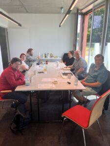 Personen sitzen um einen Konferenztisch und schauen nach vorn