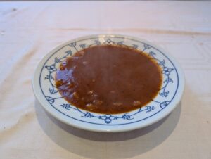 Weißer tiefer Teller voller Tomatensuppe mit Nudeln